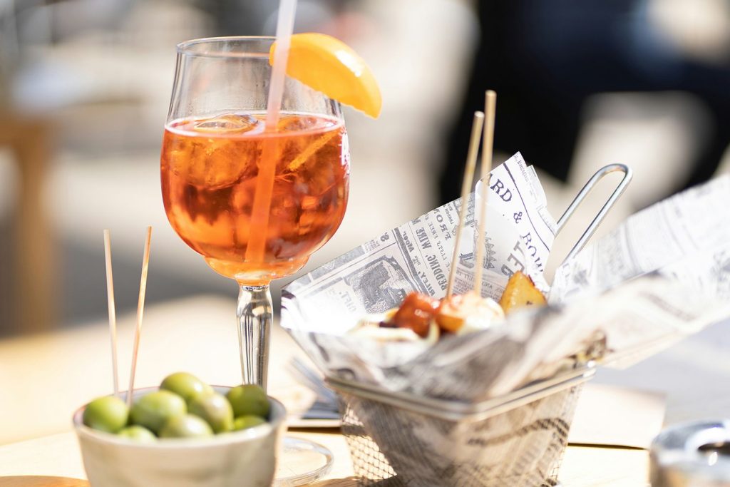 Spanish tapas on a terrace. Patatas bravas with alioli, gren olives and a gladd of aperol spritz.
