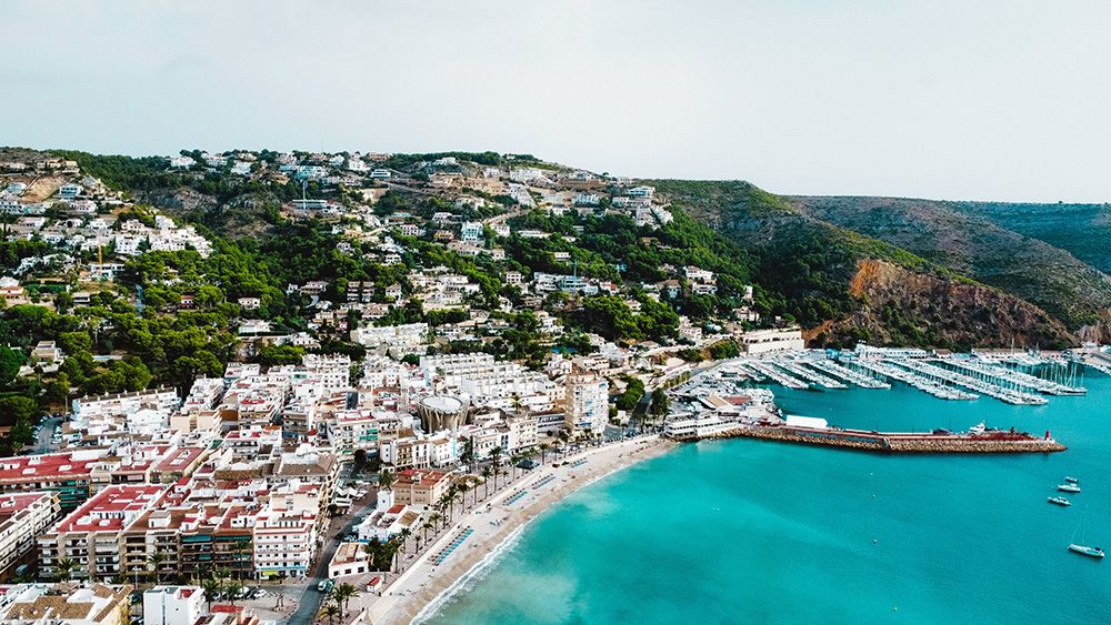 Drone image of Javea Spain's coastal city by the brightblue ocean. 