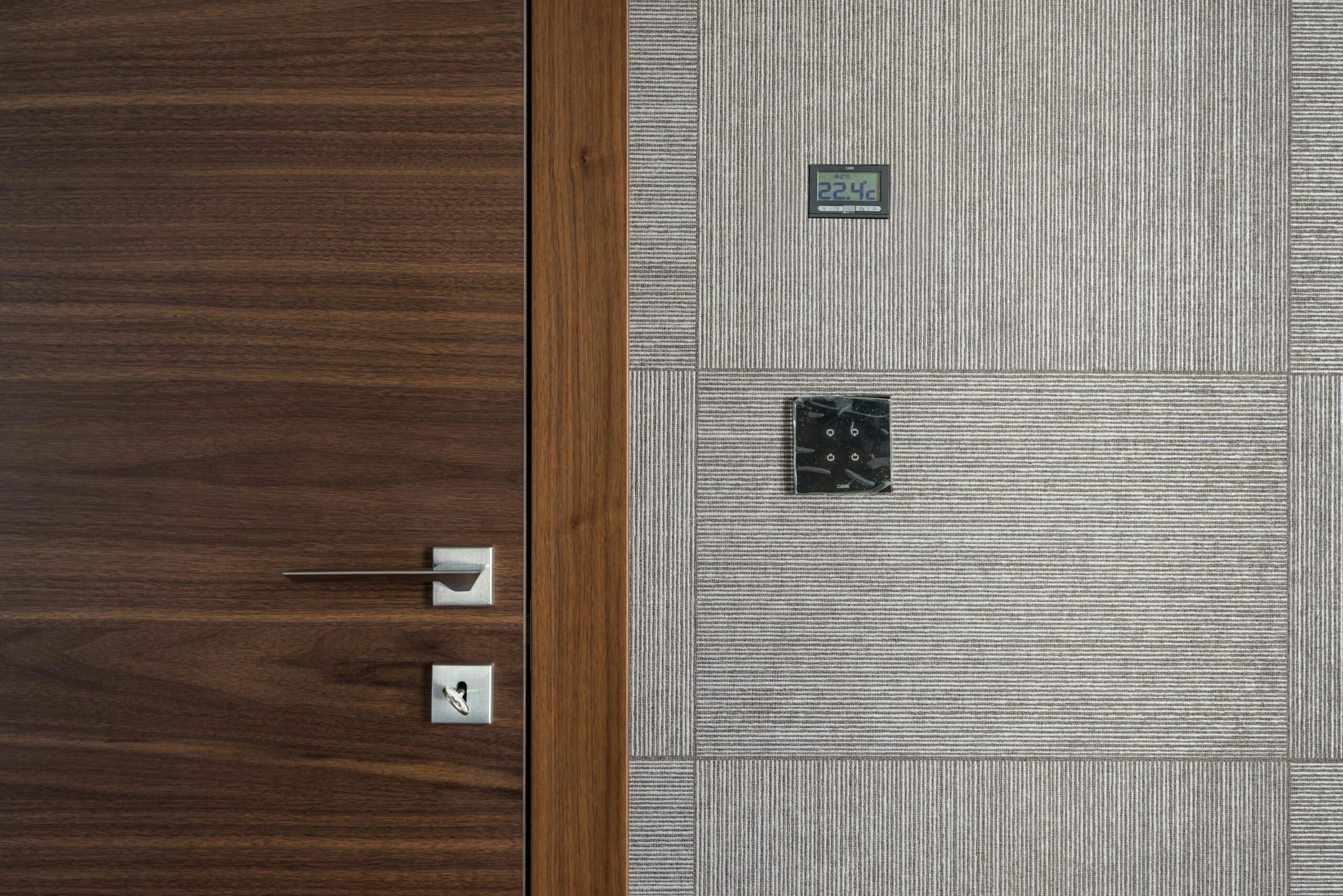 Smart home thermostat installed next to modern door, representing energy-efficient renovation for rental properties