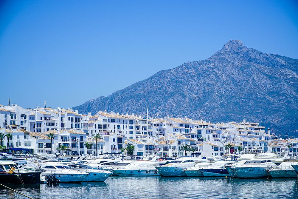 White yachts and boats on a harbour in Marbella Spain. They are floating on crystal clear blue waters at the dock.