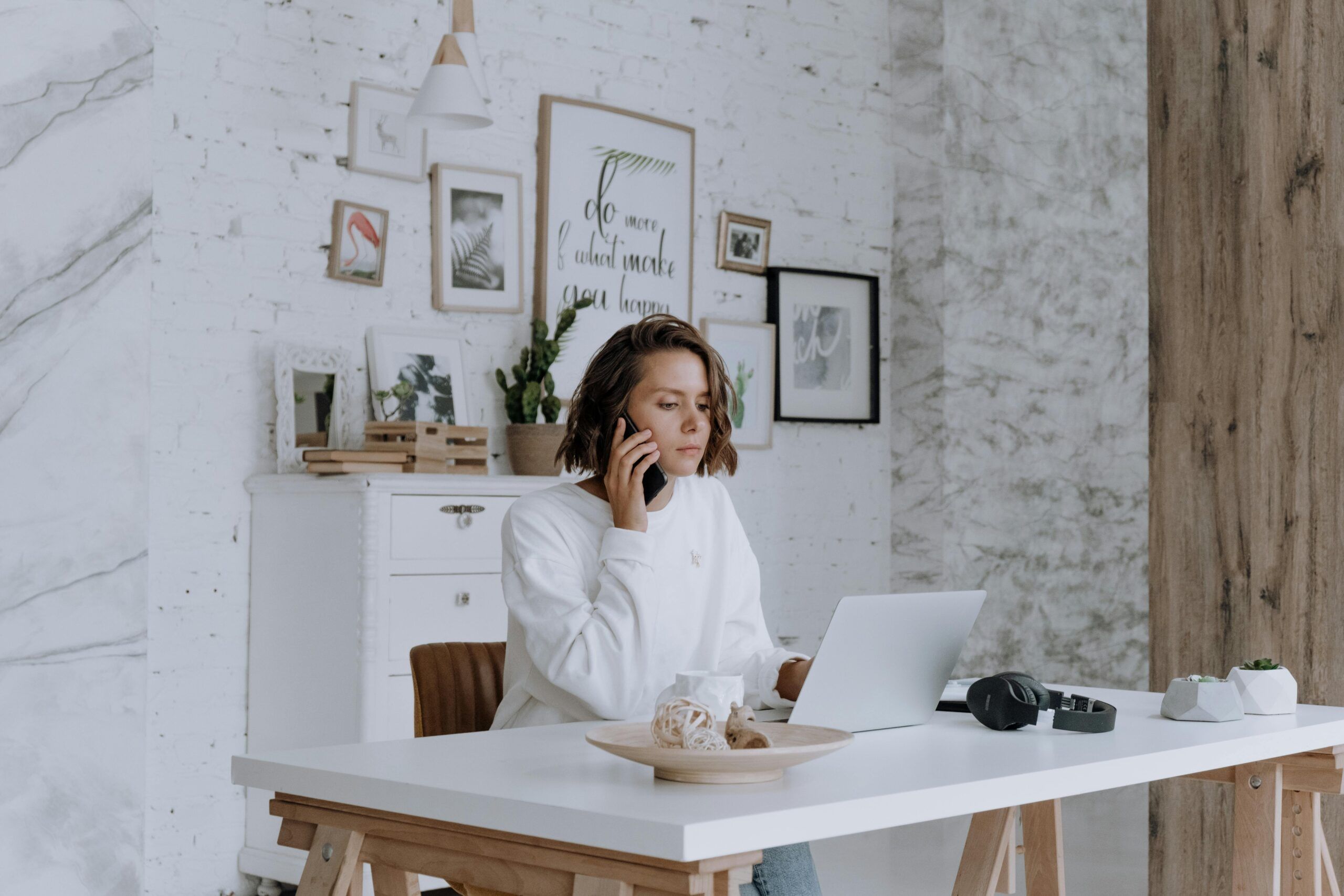 Young woman working remotely in Spain on her laptop while talking on the phone, representing expat lifestyle in Valencia