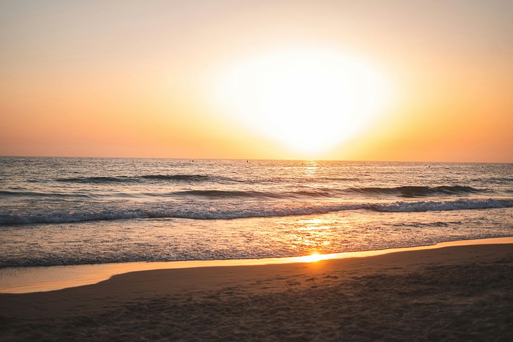 Golden sunset over the Mediterranean Sea with gentle waves rolling onto a sandy beach.
