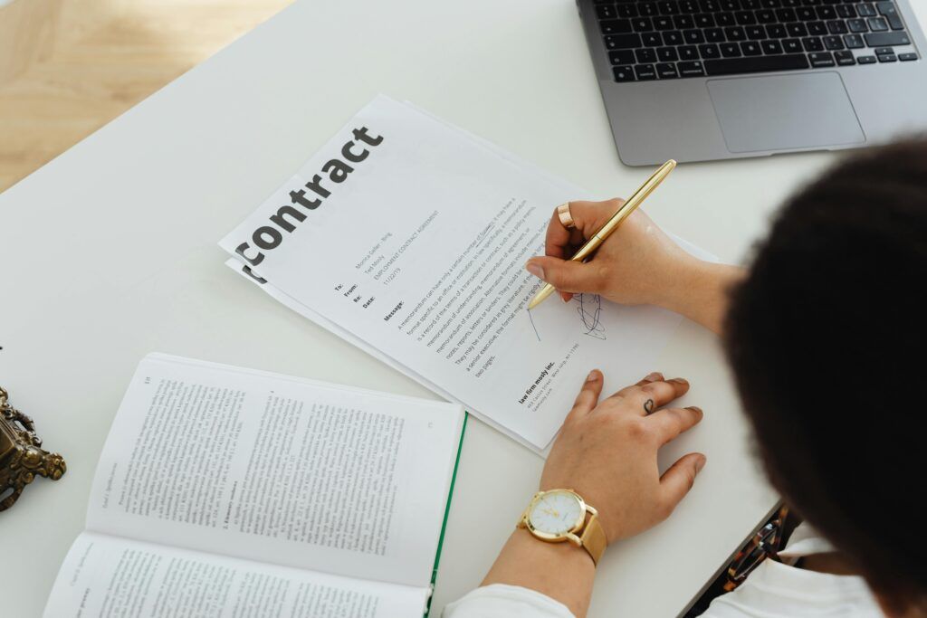 Person signing a real estate contract with laptop and documents, representing mortgage and financing opportunities in Spain