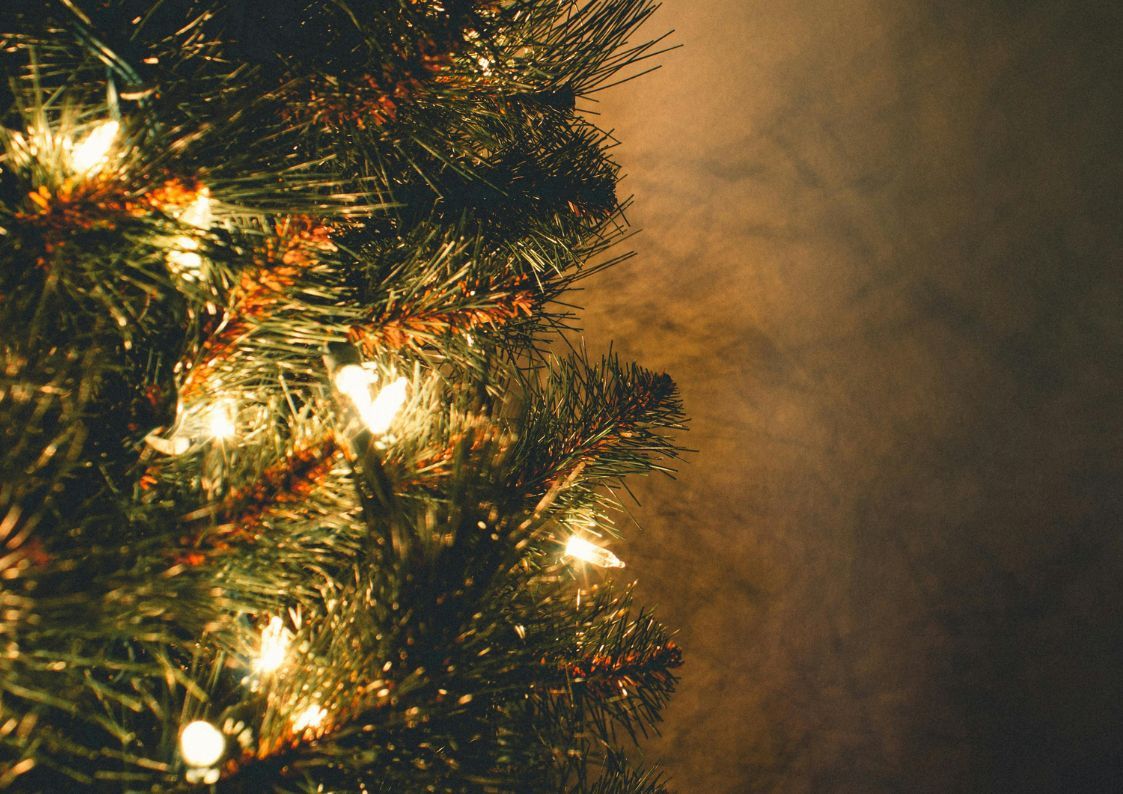 Close-up of a Christmas tree with glowing lights and festive decorations.