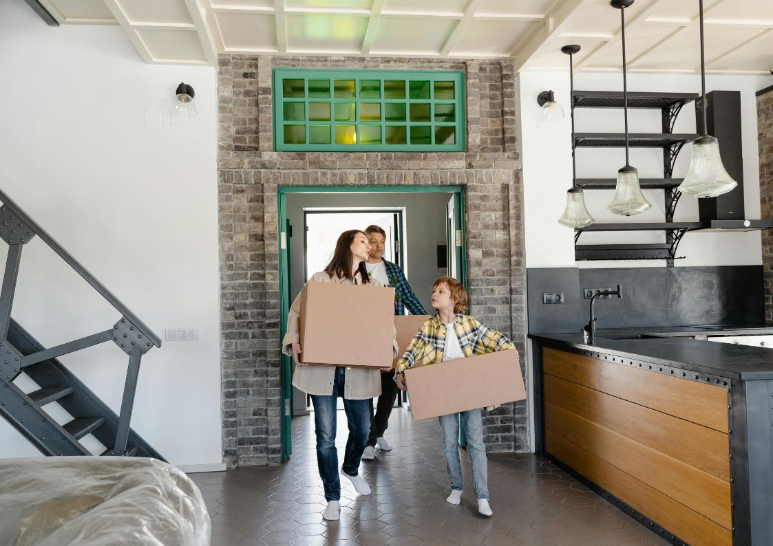 Happy family moving into their new home in Spain, carrying boxes through the doorway.