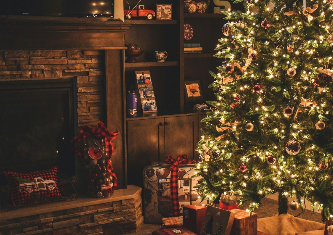 Cozy living room with decorated Christmas tree, fireplace, and wrapped gifts for the holidays.