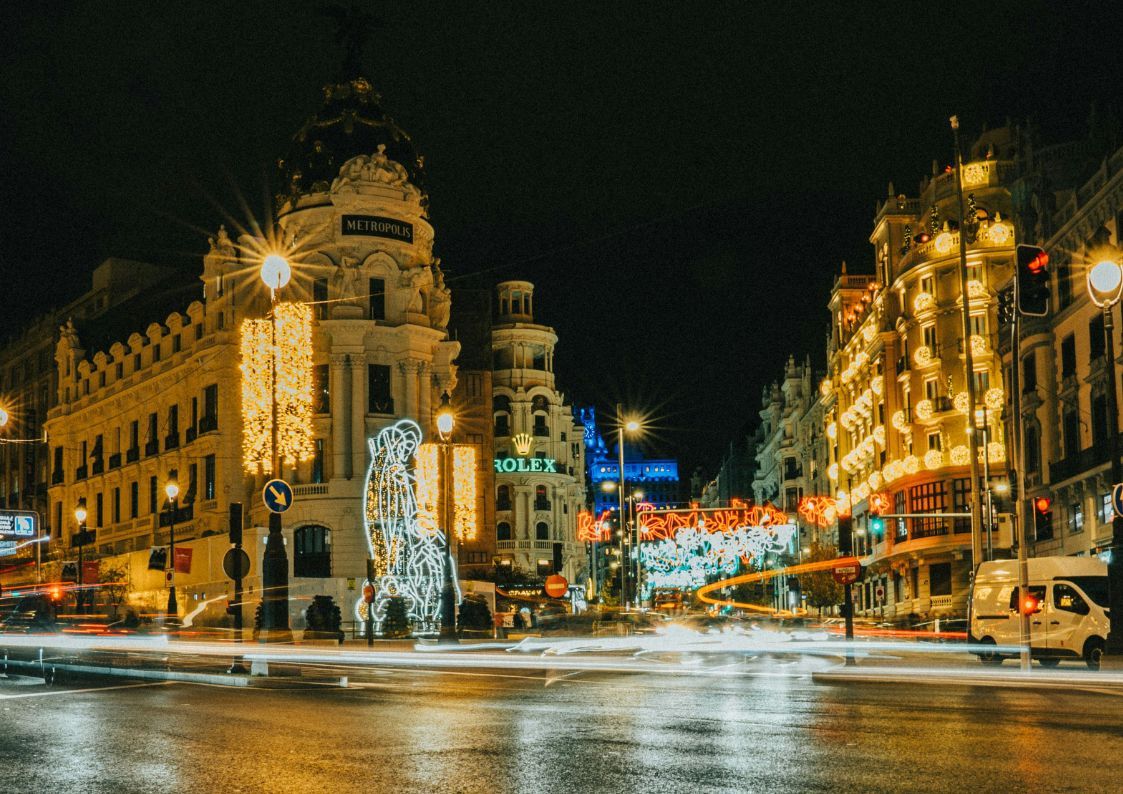 Christmas lights illuminating Madrid’s Gran Vía at night, with the Metropolis building decorated for the holidays.
