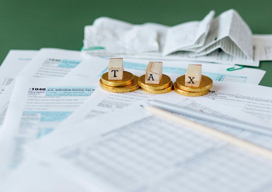 Spanish tax documents with coins spelling “TAX,” symbolizing financial requirements for visas and residency in Spain