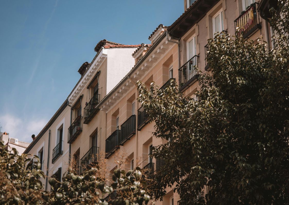 Sunlit Spanish apartment building with balconies and greenery, reflecting charming urban living in Spain.
