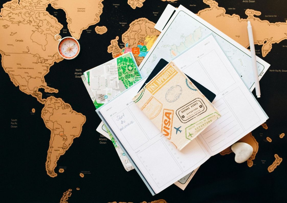 Travel flat lay with world map, passport, visa stamps, notebook, and camera, representing planning a move or long-term stay in Spain.
